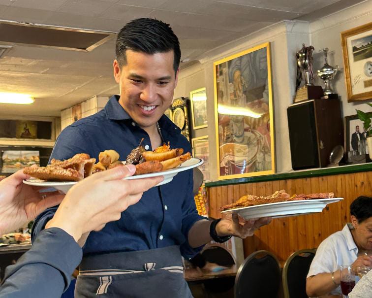 Server carrying plates of Thai food